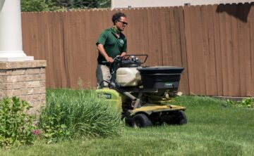 fertilization service being applied by a lawn care technician to green lawn